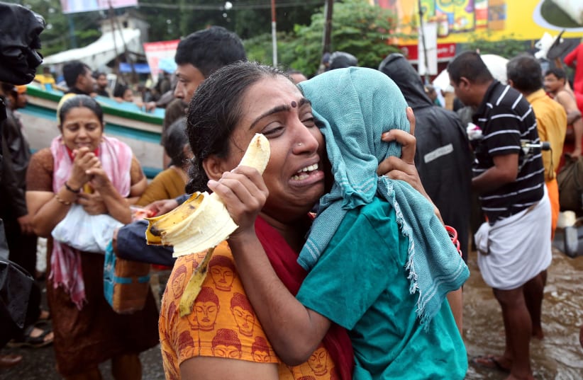 A woman cries as she holds her son after they were evacuated from a flooded area in Aluva in the southern state of Kerala, India, August 18, 2018 (photo credit: REUTERS/SIVARAM V)