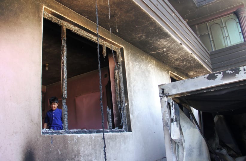 An Afghan boy is seen inside a burnt building after a Taliban attack in Ghazni city, Afghanistan August 15, 2018. (photo credit: REUTERS/MUSTAFA ANDALEB)