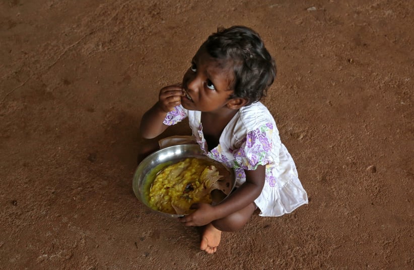 A flood-affected girl eats her food inside a school, which has been converted into a temporary relief camp, in Kochi in the southern state of Kerala, India, August 20, 2018.  (photo credit: REUTERS/SIVARAM V)