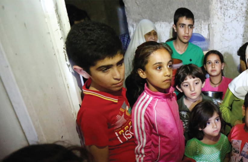 CHILDREN WAIT for meals provided through the initiative Family Kitchen, in the Al-Baqaa Palestinian refugee camp near Amman, Jordan, on June 11 (photo credit: REUTERS)