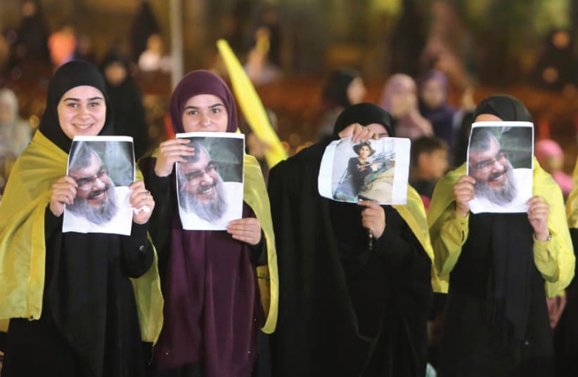 FEMALE SUPPORTERS display pictures of Hezbollah leader Sayyed Hassan Nasrallah as he remotely delivers an address, in Beirut on August 14. (photo credit: REUTERS)