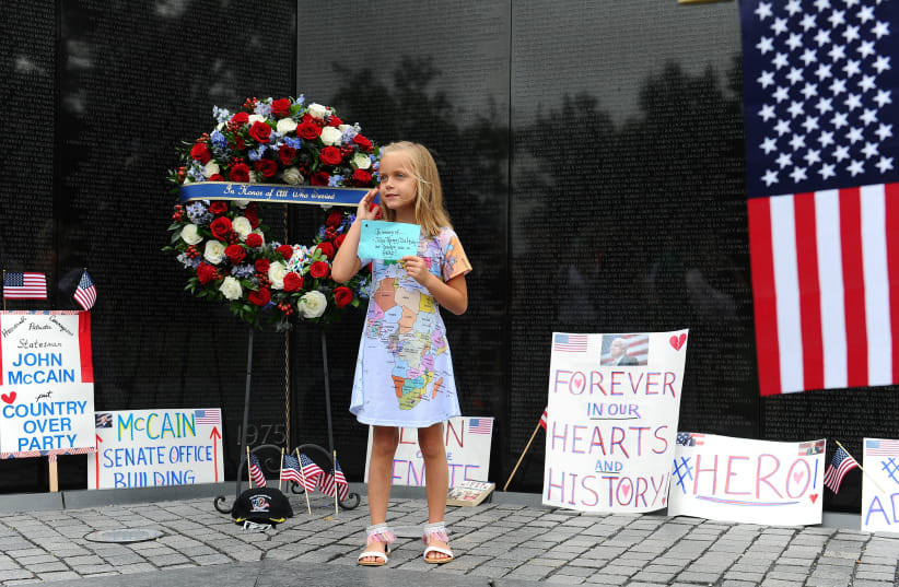 Eliana Duy, 8, FL, stands in front of the wreath that U.S. Secretary of Defense James Mattis, General John Kelly, White House Chief of Staff and Cindy McCain, wife of late Senator John McCain, lay a ceremonial wreath honoring all whose lives were lost during the Vietnam War at at the Vietnam Veteran (photo credit: MARY F. CALVERT / REUTERS)