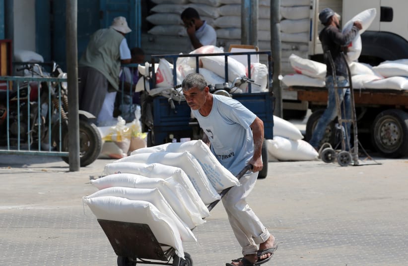 A Palestinian man pushes a cart with bags of flour at an aid distribution center run by United Nations Relief and Works Agency (UNRWA) in Khan Younis in the southern Gaza Strip September 1, 2018. (photo credit: REUTERS/IBRAHEEM ABU MUSTAFA)