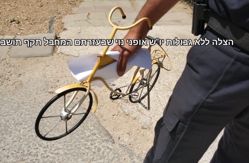 A police officer holds a toy bike with which a Palestinian man tried to attack a settler in Tekoa, September 2018 (photo credit: UNITED HATZALAH WEST BANK)