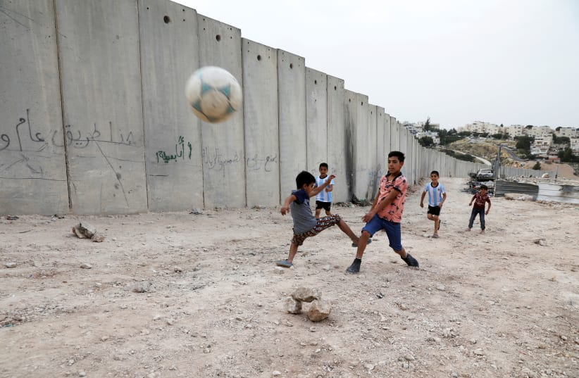 Nassim Ammour, 11, scores a goal as he plays with friends next to the Israeli barrier in the Shuafat refugee camp in east Jerusalem, May 4, 2018 (photo credit: AMMAR AWAD/REUTERS)