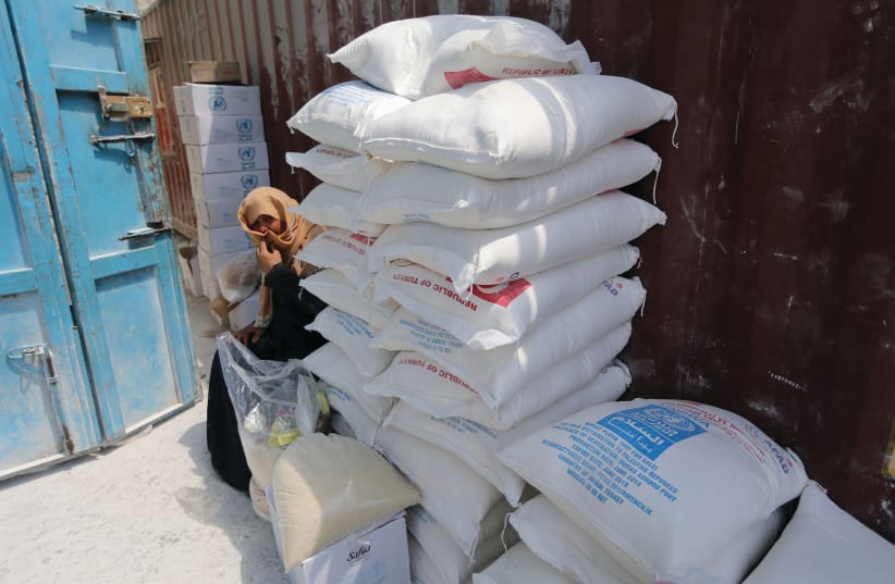 A PALESTINIAN woman sits next to bags of UNRWA flour (photo credit: REUTERS)