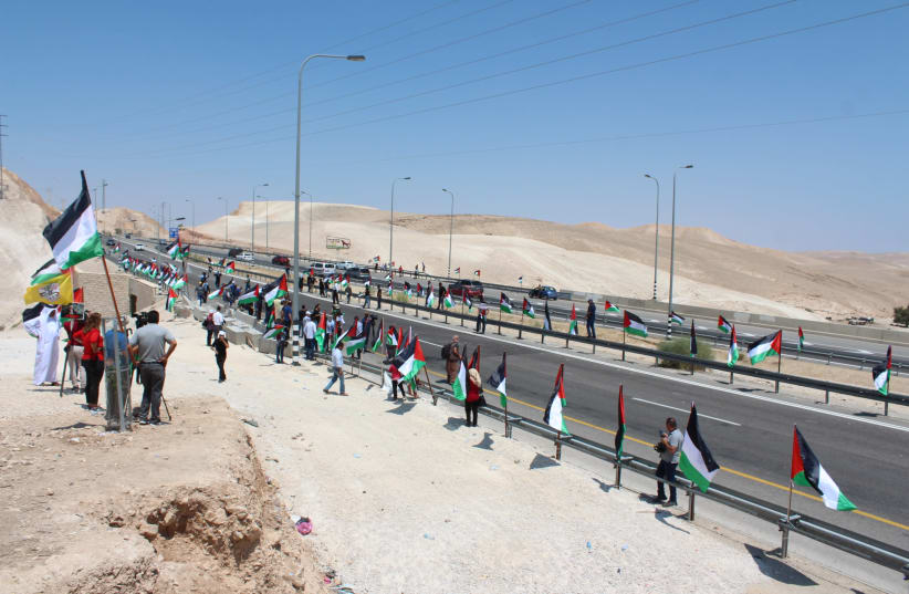 Protestors raising Palestinian flags at Bedouin village Khan al-Ahmar designated for demolition, September 2018 (photo credit: ELIE AVIDOR/COMBATANTS FOR PEACE)