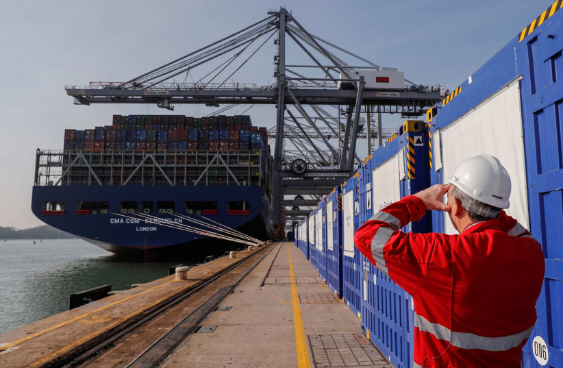 Freight containers are seen on a freight container ship as a worker looks on at DP World, Southampton Docks, in Southampton, Britain, March 27, 2017 (photo credit: REUTERS/EDDIE KEOGH)