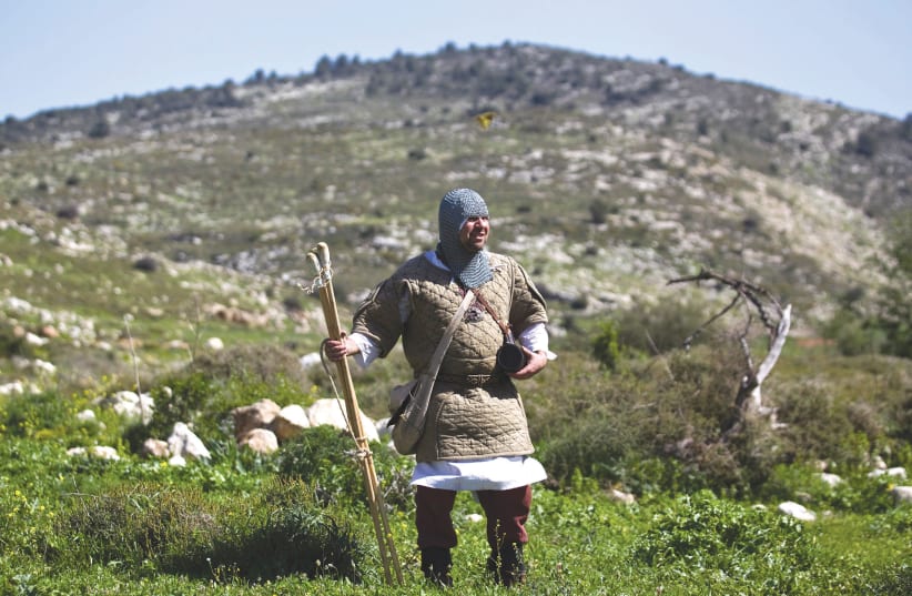 A MAN dressed up as a Crusader walks in a field during a lead up to a re-enactment of the battle of the Horns of Hattin. (photo credit: REUTERS)