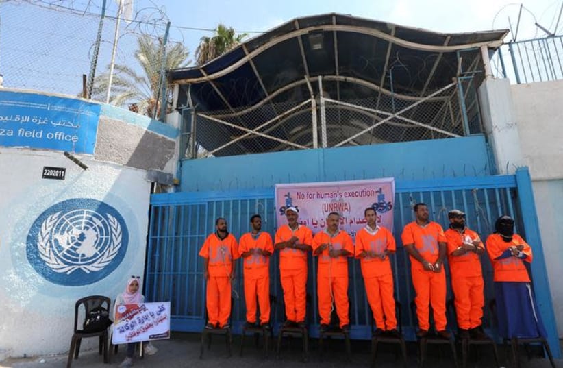Palestinian employees of United Nations Relief and Works Agency (UNRWA) wear orange jumpsuits as they protest against job cuts, outside UNRWA headquarters in Gaza City September 19, 2018 (photo credit: IBRAHEEM ABU MUSTAFA / REUTERS)