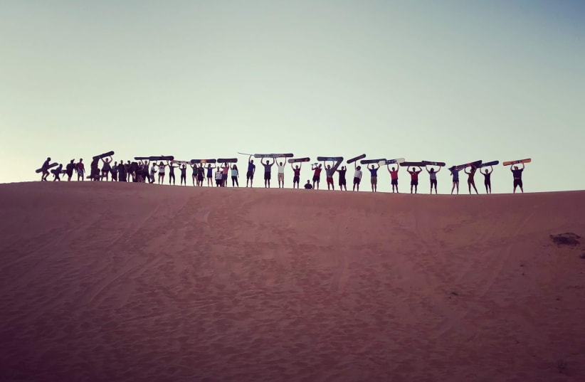 A group of Birthright Israel participants go sandboarding at Dror Bamidbar in the Negev desert. (photo credit: LEAH GRAFF)