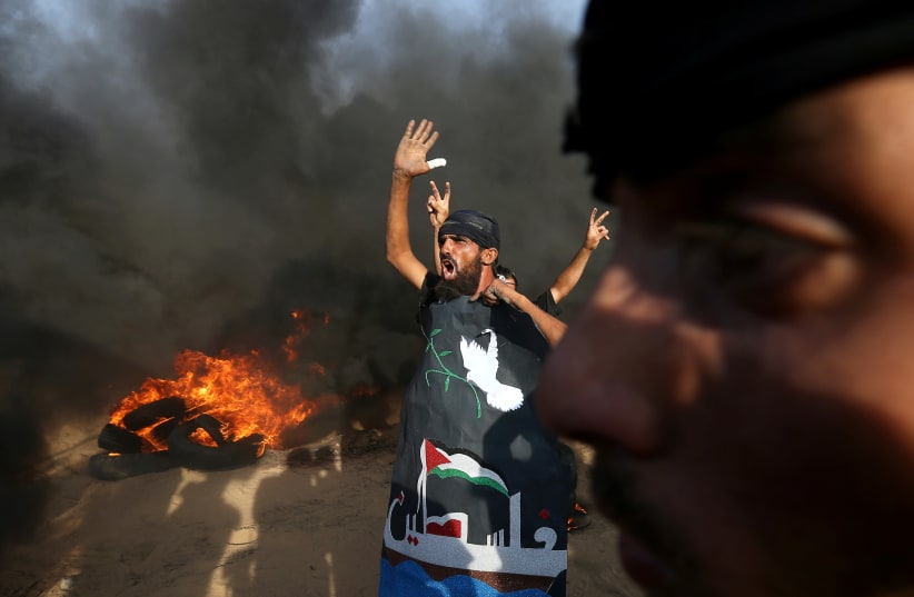 A Palestinian reacts during a protest calling for lifting the Israeli blockade on Gaza and demanding the right to return to their homeland, at the Israel-Gaza border fence in the southern Gaza Strip October 5, 2018.  (photo credit: IBRAHEEM ABU MUSTAFA / REUTERS)