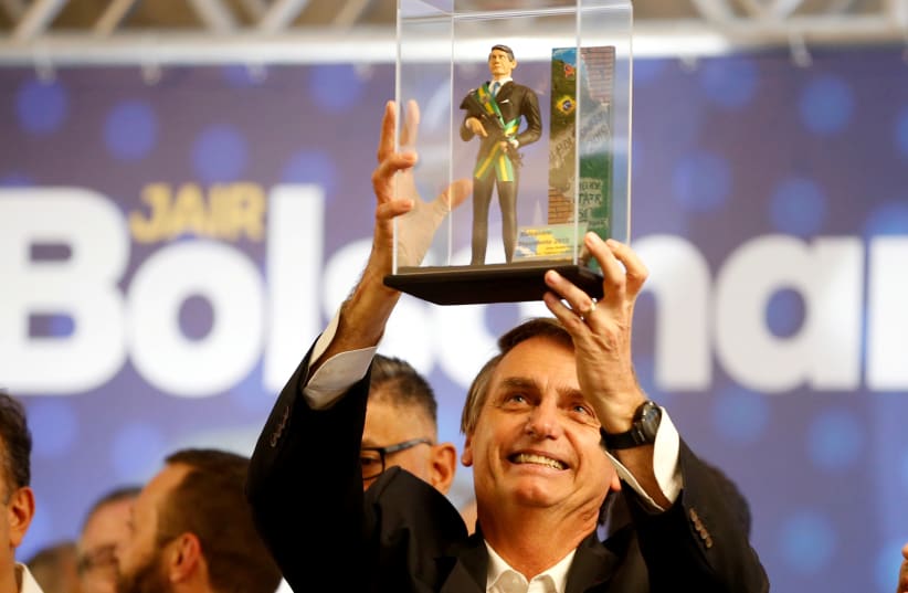 Presidential candidate Jair Bolsonaro, shows a doll of himself during a rally in Curitiba, Brazil March 29, 2018.  (photo credit: REUTERS)