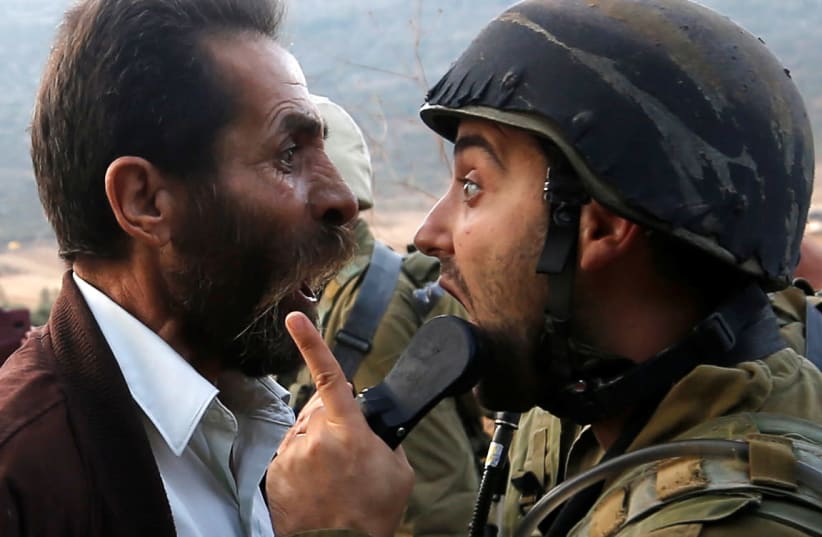 A Palestinian man argues with an Israeli soldier during clashes over an Israeli order to shut down a Palestinian school near Nablus in  West Bank October 15, 2018.  (photo credit: MOHAMAD TOROKMAN/REUTERS)