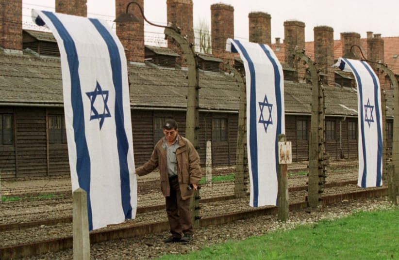 A MAN stands amid Israeli flags displayed outside Auschwitz in 1998. (photo credit: REUTERS)