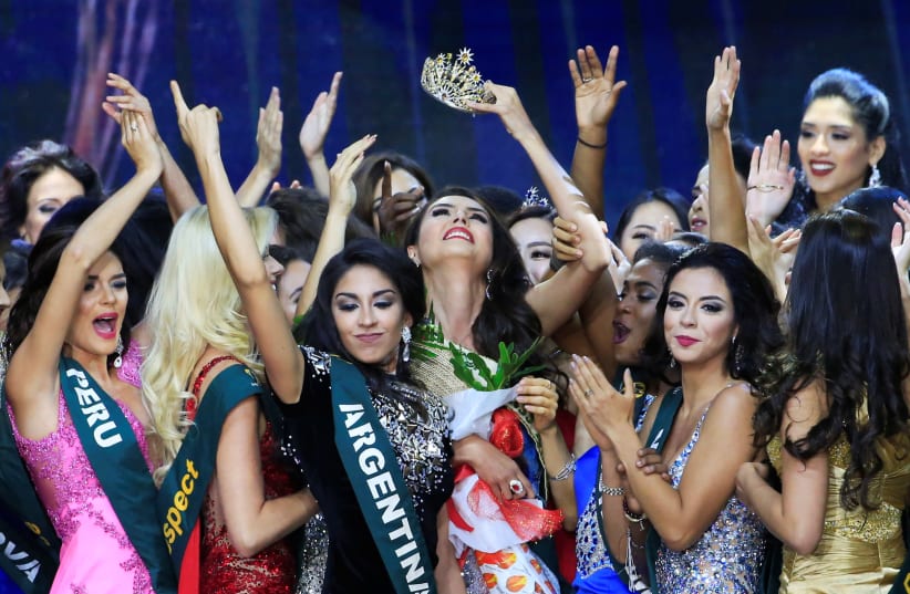 Miss Colombia Michelle Gomez (C), crowned 2016's Miss Earth Air, raises her crown while other contestants greet her (photo credit: REUTERS/ROMEO RANOCO)