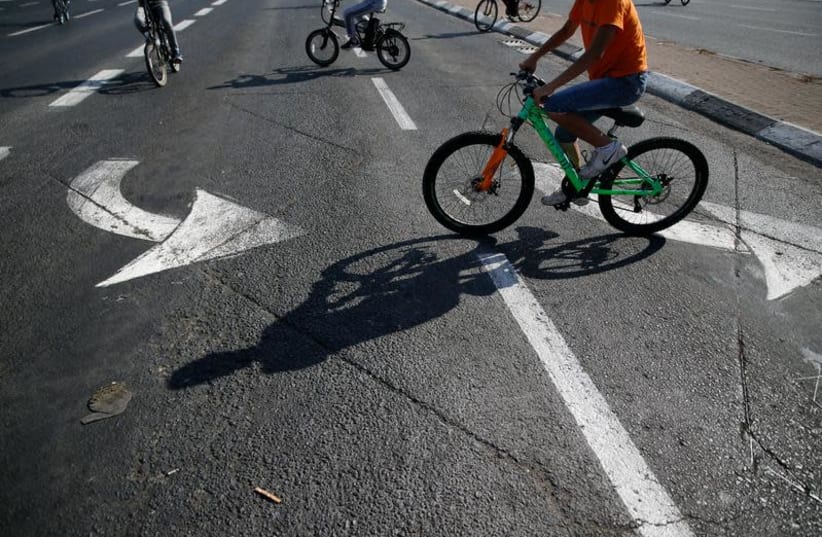 Children ride their bicycles on an empty road during the Jewish holiday Yom Kippur in Jerusalem, September 30, 2017. (photo credit: REUTERS/AMMAR AWAD)