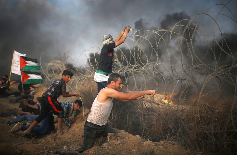 Disable Palestinian tries to remove Israeli wire during a protest at the Israel-Gaza border fence in Gaza. (photo credit: MOHAMMED SALEM/ REUTERS)