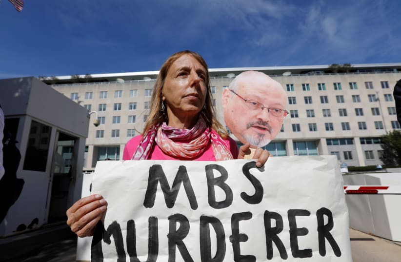 "Code Pink" activist group co-founder Medea Benjamin participates in a demonstration calling for sanctions against Saudi Arabia and against the disappearance of Saudi journalist Jamal Khashoggi while holding a photo of Khashoggi outside the U.S. State Department in Washington, October 19, 2018 (photo credit: KEVIN LAMARQUE/REUTERS)