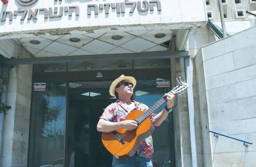 News anchor Arieh O’Sullivan plays the blues in front of the Israel Broadcasting Authority’s former headquarters in Jerusalem to protest the closure of IBA English News last year (photo credit: MARC ISRAEL SELLEM)