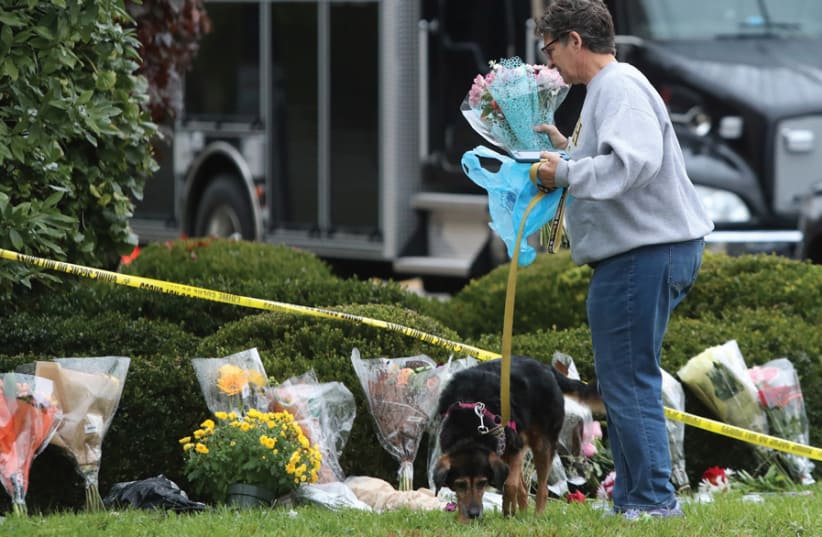 A WOMAN brings flowers to an impromptu memorial at the Tree of Life Synagogue following the previous day’s shooting at the synagogue in Pittsburgh, on October 28. (photo credit: REUTERS)