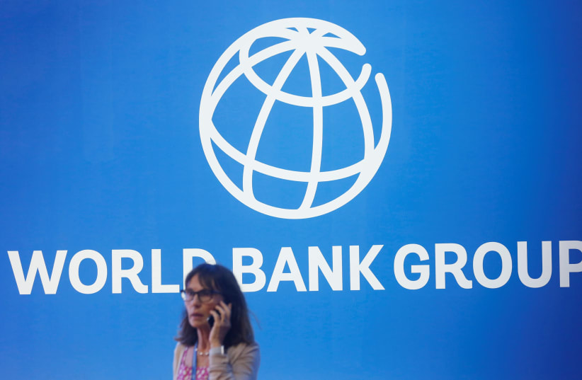 A participant stands near a logo of World Bank at the International Monetary Fund - World Bank Annual Meeting 2018 (photo credit: REUTERS/JOHANNES P. CHRISTO)