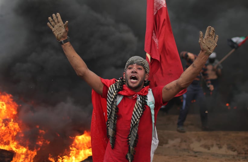 A Palestinian demonstrator reacts during a protest calling for lifting the blockade on Gaza, at the Israel-Gaza border fence in Gaza October 26, 2018 (photo credit: MOHAMMED SALEM/REUTERS)