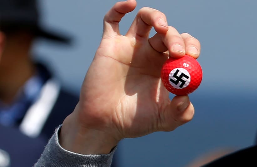 A protester holds up golf balls with a swastika as he is removed from a press conference by Republican presidential candidate Donald Trump at Turnberry Golf course in Turnberry, Scotland, June 24, 2016.  (photo credit: CARLO ALLEGRI/REUTERS)