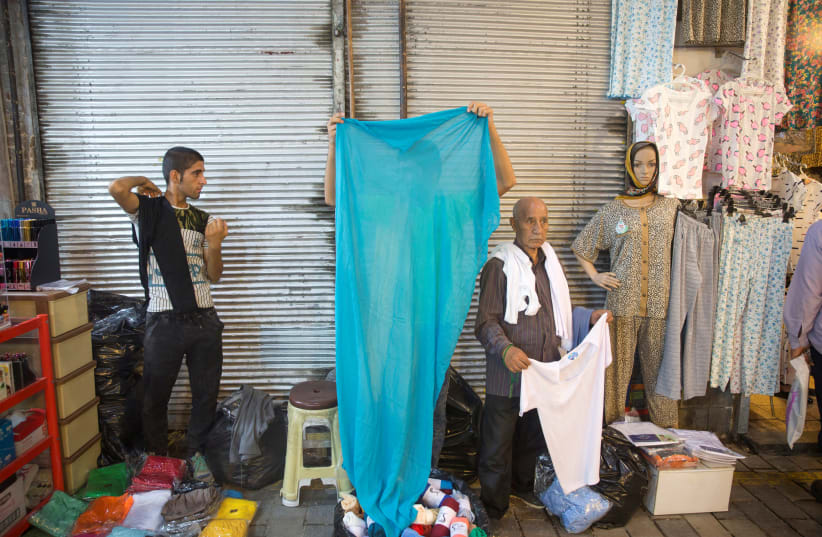 An Iranian vendor sells clothes at the Grand Bazaar in the center of Tehran, Iran, August 2, 2017 (photo credit: NAZANIN TABATABAEE YAZDI/ TIMA VIA REUTERS)