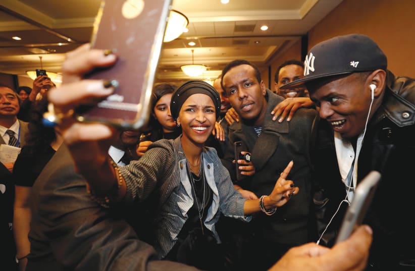 DEMOCRATIC CONGRESSIONAL candidate Ilhan Omar takes a selfie with supporters after appearing at her election party.  (photo credit: REUTERS)