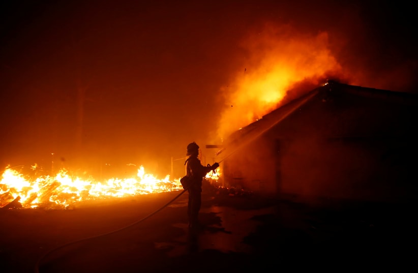A firefighter battles the Woolsey Fire in Malibu, California, U.S. November 9, 2018. The fire destroyed dozens of structures, forced thousands of evacuations and closed a major freeway.  (photo credit: ERIC THAYER/ REUTERS)
