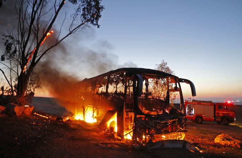 A picture taken on November 12, 2018 shows a bus set ablaze after it was hit by a rocket fired from the Gaza Strip (photo credit: MENAHEM KAHANA / AFP)