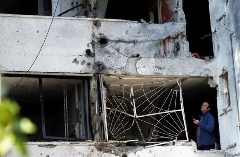 A man stands inside a building damaged by a rocket fired from the Gaza Strip overnight, in the Israeli city of Ashkelon November 13, 2018 (photo credit: RONEN ZVULUN / REUTERS)