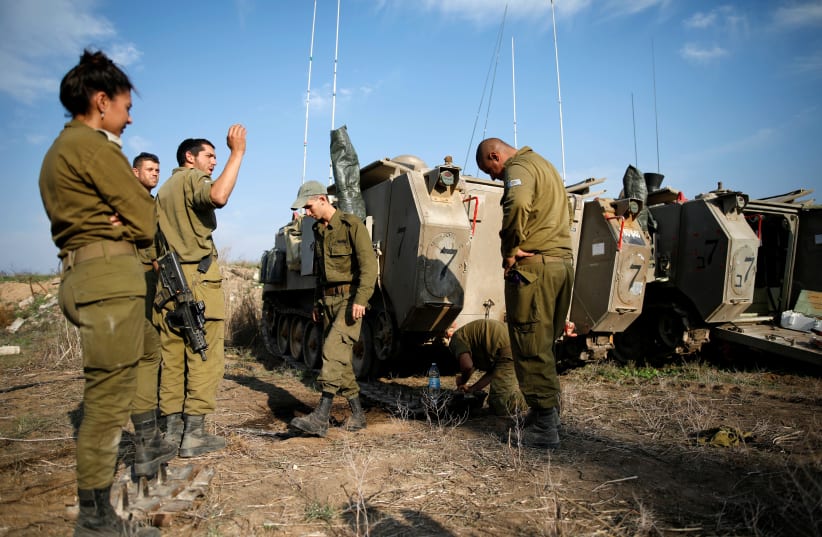 Israeli soldiers stand next to armoured personnel carriers (APC) in a field in southern Israel, near the border with Gaza, November 13, 2018 (photo credit: AMIR COHEN/REUTERS)