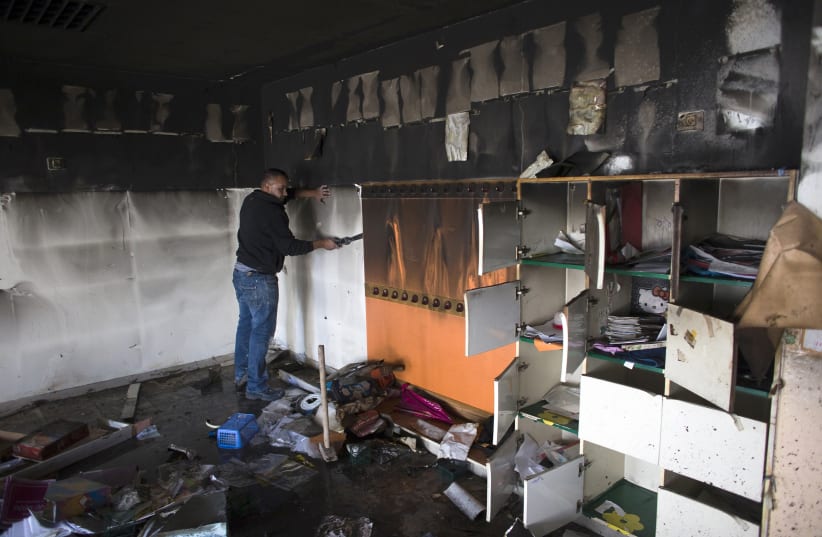 A worker cleans up in a torched classroom in an Arab-Jewish school in Jerusalem November 30, 2014 (photo credit: RONEN ZVULUN/REUTERS)