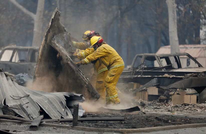 Cal Fire firefighters comb through a house destroyed by the Camp Fire in Paradise (photo credit: REUTERS/TERRAY SYLVESTER)