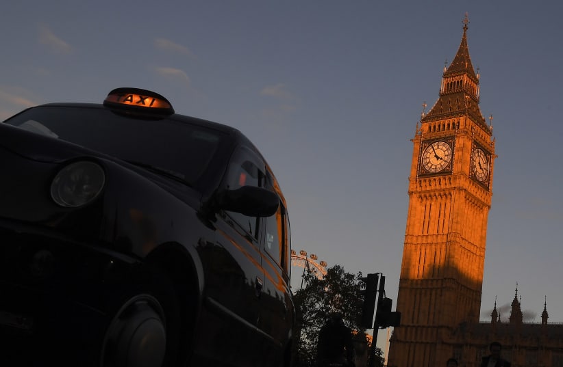 A London black cab taxi drives past Big Ben and the Houses of Parliament in late afternoon sunlight in London, Britain, November 10, 2016.  (photo credit: REUTERS/TOBY MELVILLE)