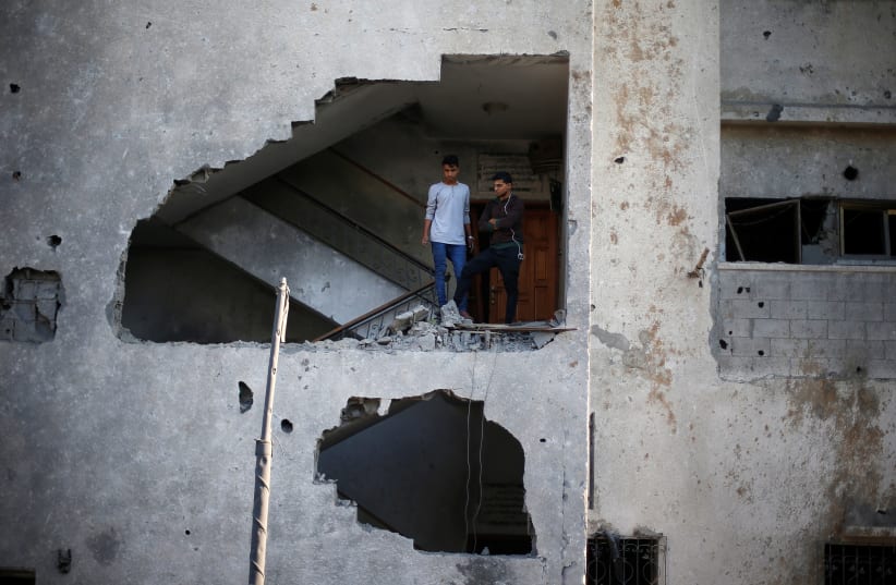 Palestinians look out of their house that was damaged in an Israeli air strike, in Gaza City November 13, 2018 (photo credit: REUTERS/SUHAIB SALEM)