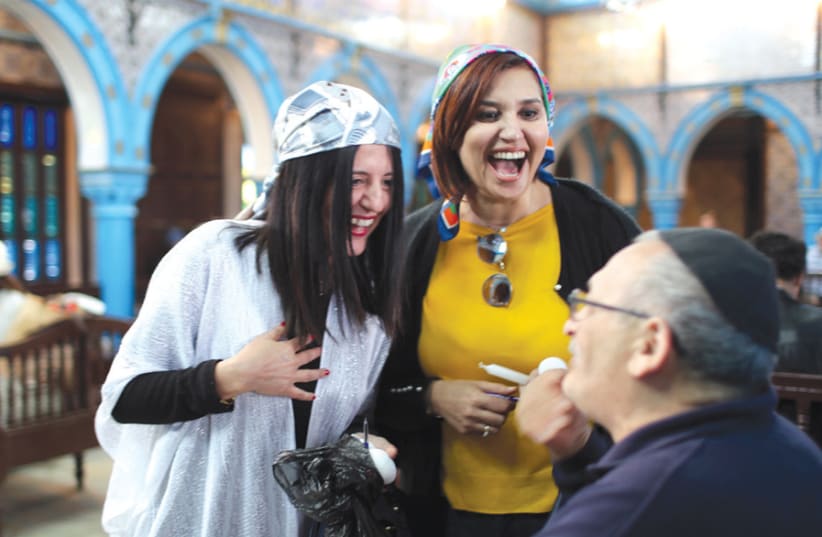 Two Tunisian Muslim women chat with a Jewish man at the El Ghriba Synagoguge (photo credit: AHMED JADALLAH / REUTERS)