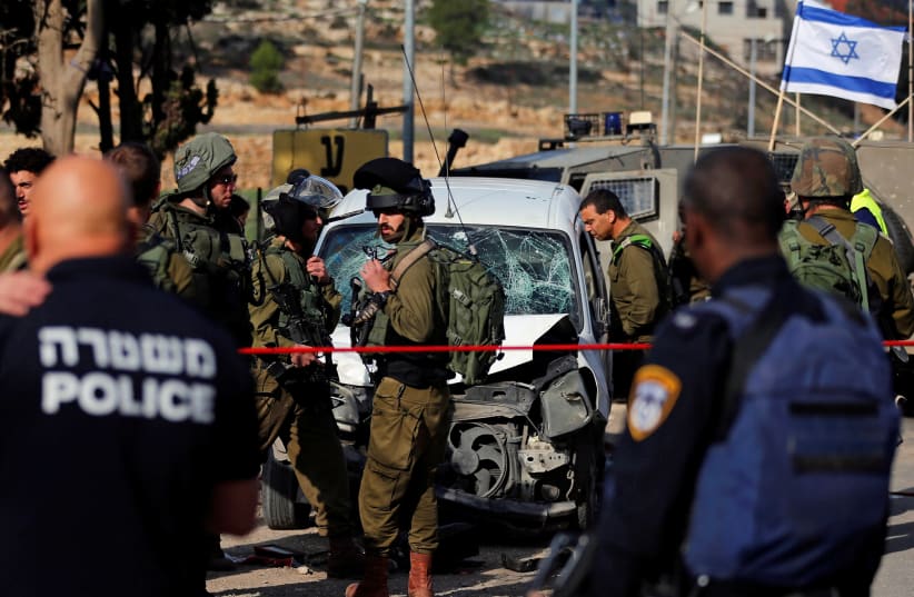 Israeli policemen inspect the scene of a car-ramming attack near Hebron, November 26, 2018 (photo credit: AMMAR AWAD/REUTERS)