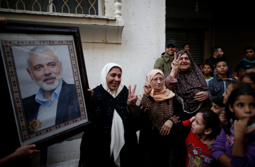 Palestinians celebrate the resignation of Israel's Defence Minister Avigdor Lieberman as a woman holds a picture of Hamas Chief Ismail Haniyeh, in Gaza City November 14, 2018 (photo credit: SUHAIB SALEM/REUTERS)