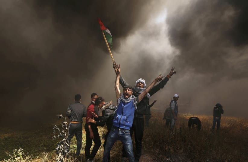 Palestinian demonstrators shout during clashes with Israeli troops at a protest demanding the right to return to their homeland, at the Israel-Gaza border east of Gaza City, April 6, 2018 (photo credit: REUTERS/MOHAMMED SALEM)