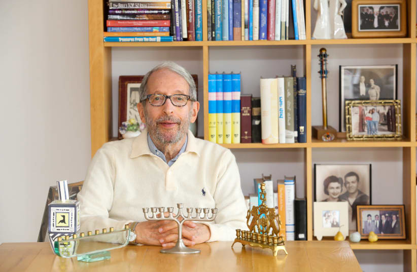 Rabbi Dov Peretz Elkins shows off several of his hanukkiot in his Jerusalem apartment; behind him are some of the 51 books he has published (photo credit: MARC ISRAEL SELLEM/THE JERUSALEM POST)