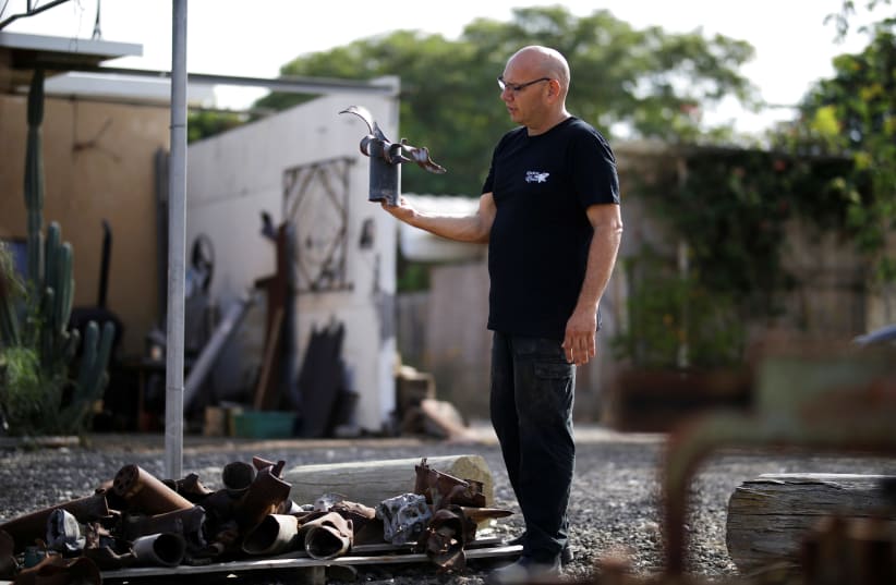 Israeli metal sculptor Yaron Bob looks at remains of rockets and mortar shells fired into Israel by Palestinian militants from Gaza, outside his studio in Yated, southern Israel  (photo credit: AMIR COHEN/REUTERS)