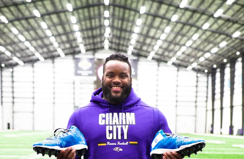Baltimore Ravens’ Michael Pierce holding his Israeli-themed cleats (photo credit: ISRAEL COLLECTIVE)