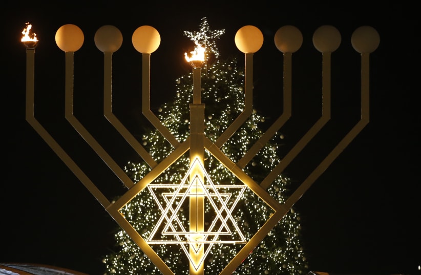 A giant menorah stands in front of a Christmas tree at the Brandenburg gate to celebrate Hanukkah in Berlin December 16, 2014 (photo credit: REUTERS/FABRIZIO BENSCH)