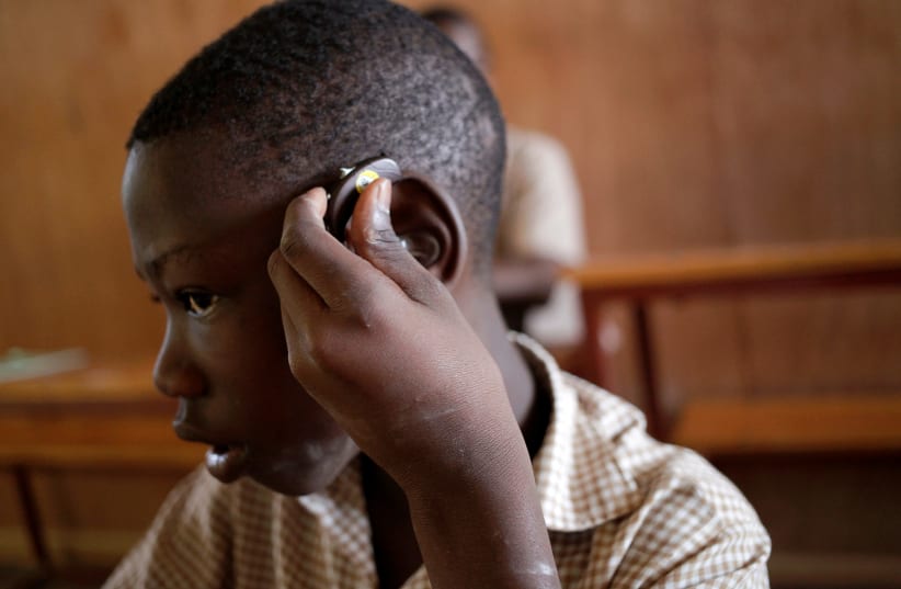 A deaf pupil puts a hearing aid on his ear at the Mission de L'Espoir school in Leveque, Haiti, April 11, 2016. (photo credit: REUTERS/ANDRES MARTINEZ CASARES)