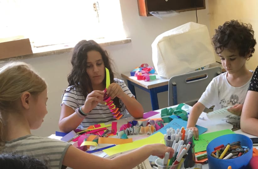 A staff member provides assistance during an artsand- crafts workshop, helping pupils meet their desired learning goals. (photo credit: JERUSALEM SUDBURY DEMOCRATIC SCHOOL)