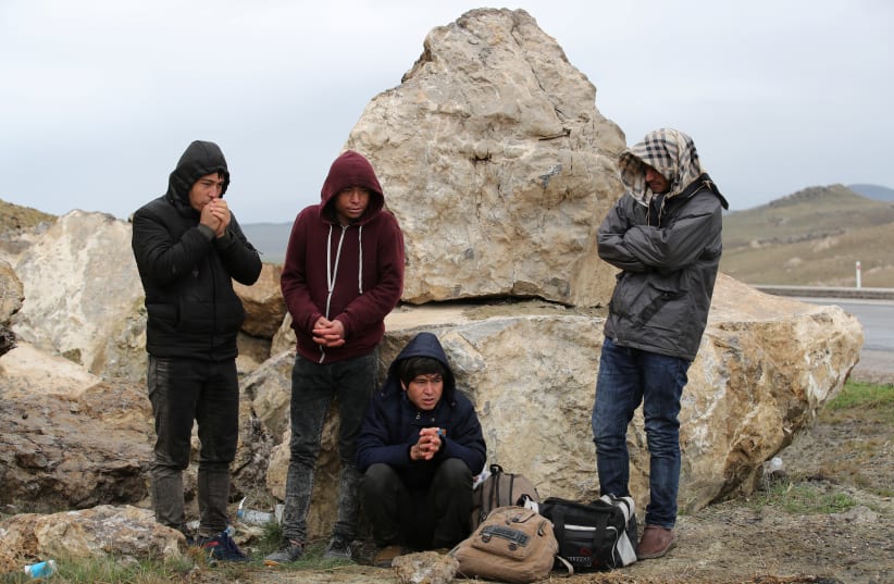 A group of Afghan migrants rest, during a break from their walk, on a main road, after crossing the Turkey-Iran border near Dogubayazit, Agri province, eastern Turkey, April 11, 2018. Picture taken April 11, 2018 (photo credit: REUTERS/UMIT BEKTAS)