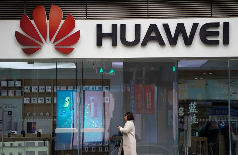 A woman walks by a Huawei logo at a shopping mall in Shanghai, China December 6, 2018 (photo credit: ALY SONG/REUTERS)